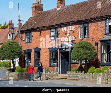 Zwei Frauen, die am Queen & Castle Pub auf Castle Green in Kenilworth, Warwickshire, England, vorbeigehen Stockfoto