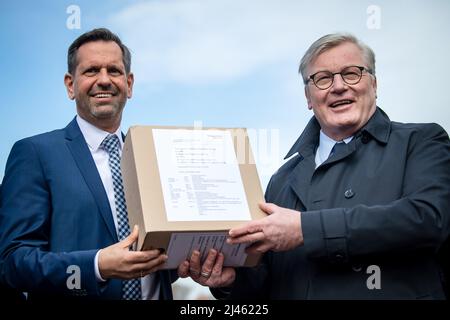 12. April 2022, Niedersachsen, Stade: Bernd Althusmann (CDU, r), Verkehrsminister von Niedersachsen, und Olaf Lies (SPD), Umweltminister von Niedersachsen, halten eine Kiste mit den Genehmigungsunterlagen für den Importterminal für Flüssigerdgas in der Hand. Bis 2026 soll in Stade ein Importterminal für Flüssiggas (LNG) errichtet werden. Von dort werden dann bis zu 13,3 Milliarden Kubikmeter Gas pro Jahr in die Netze geleitet - rund 15 Prozent des deutschen Gasbedarfs. Das Betreiberkonsortium Hanseatic Energy Hub (HEH) hat die Genehmigungsunterlagen bei der zuständigen State Trade Superv eingereicht Stockfoto