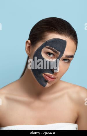 Porträt einer schönen Frau mit einer schwarzen Maske aus Ton auf ihrem Gesicht. Mädchen Modell Schönheit Gesicht mit kosmetischen Maske. Hautpflege . Spa-Behandlung. Cosmetol Stockfoto