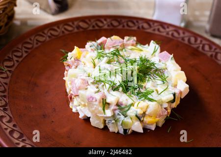 Salat mit Erbsen und Mayonnaise, serviert in einem Zylinder auf einem Tonteller Stockfoto