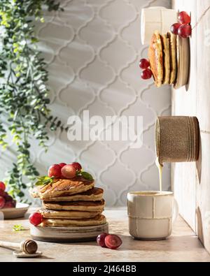 Konzept der Fotografie in drei Ebenen. Stapel von Pfannkuchen mit Honig und Trauben zum Frühstück. Vertikale Ausrichtung Stockfoto