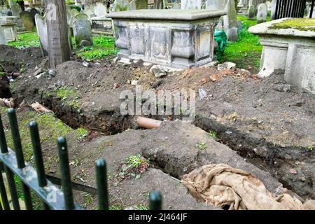 Graben als Ersatz für undichte Wasserleitungen auf dem Friedhof von Bunhill Fields 2022. April London EC1 England Großbritannien KATHY DEWITT Stockfoto