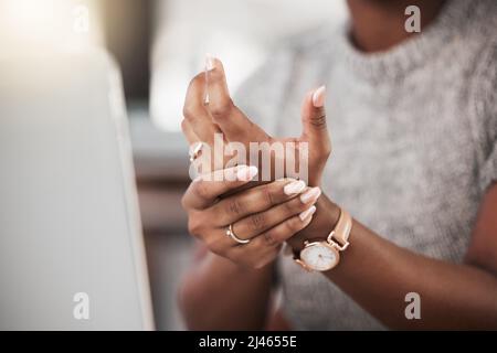 Zu viel Tipparbeit fordert ihren Tribut. Aufnahme einer Geschäftsfrau mit Schmerzen am Handgelenk, während sie in einem modernen Büro einen Laptop benutzt. Stockfoto