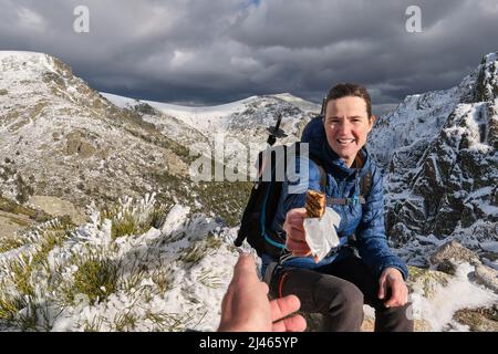 Dame, die Schokolade schenkt, während sie in den Bergen sitzt Stockfoto