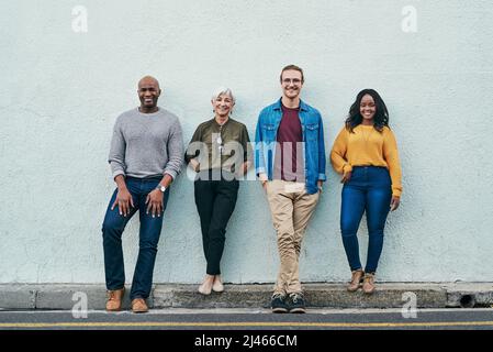 Nichts kann uns im Weg stehen. Ganzkörperaufnahme einer Gruppe von Geschäftsleuten, die im Freien an einer Wand Schlange stehen. Stockfoto