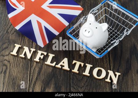 Inflation in Briefen mit Sparschwein im Warenkorb und Flagge des Vereinigten Königreichs geschrieben Stockfoto