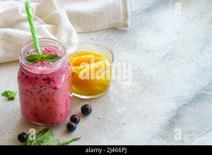 Smoothie mit schwarzer Johannisbeere mit Mango, Kokosmilch und Minze auf verputztem Hintergrund mit Kopierfläche Stockfoto