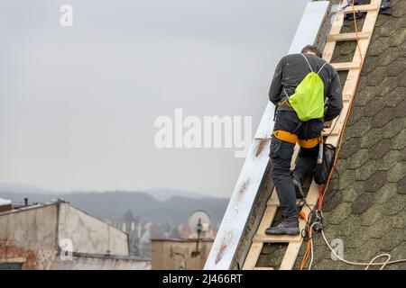 Ein Mann arbeitet an der Dachreparatur, installiert Blech auf der Gieblechwand Stockfoto