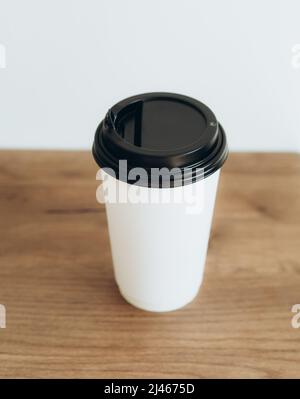 Tasse Kaffee in weißen Papierbecher auf Holztisch zu gehen. Morgenkaffee im Café Platz für Text. Stockfoto