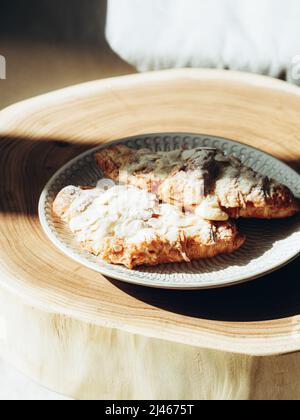 Traditionelles französisches Frühstückscroissant mit Mandeln auf dem Holztisch bei Sonnenlicht Stockfoto