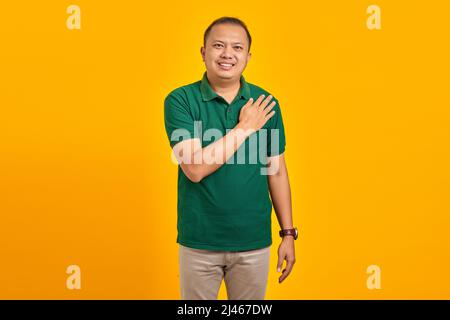 Porträt eines lächelnden asiatischen jungen Mannes, der die Hände auf gelbem Hintergrund plissiert Stockfoto