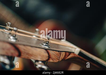 Eine Nahaufnahme des Kopfstocks einer akustischen Gitarre, die den Ankerwinde mit einer Bronzesaite zeigt. Stockfoto