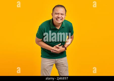 Attraktiver junger Mann aus Asien, der auf gelbem Hintergrund lustig lacht Stockfoto