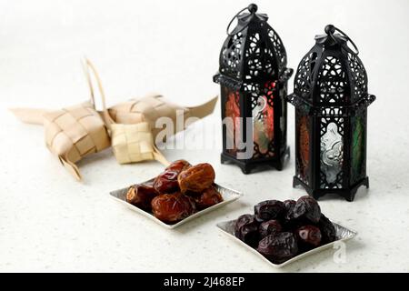 Ramadan Kareem und iftar muslimisches Essen, Urlaubskonzept. Tisch mit Ketupat und getrockneten Früchten und Lattern mit Kerzen. Idee zur Feier Stockfoto