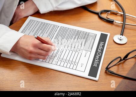Medizinische Checkliste. Ärztin hält einen Stift, Nahaufnahme, Bürotisch aus Holz im Hintergrund. Weibliche Hand, die das Dokument ausfüllt, Platz zum Kopieren Stockfoto