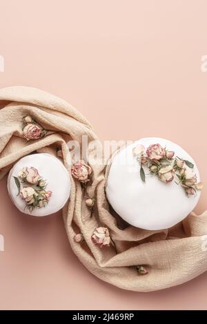 Glasierte Osterkuchen mit trockenen Teebrosen auf pastellfarbenem Hintergrund. Osterkomposition mit Kuchen, Rosen und Serviette. Osterhintergrund mit Platz zum Kopieren für Ihr Design. Stockfoto