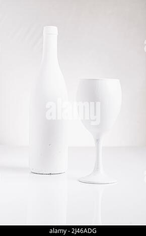 Weiß lackierte Flasche und Weinglas in einer guten Schlüsseleinstellung. Stockfoto