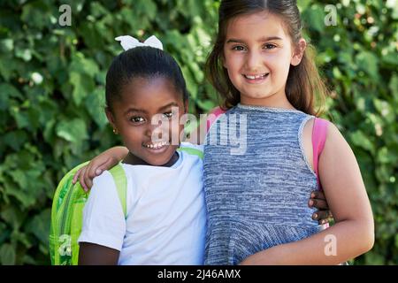 Freunde für immer. Aufnahme von zwei kleinen Mädchen, die draußen in der Natur Rucksäcke tragen. Stockfoto