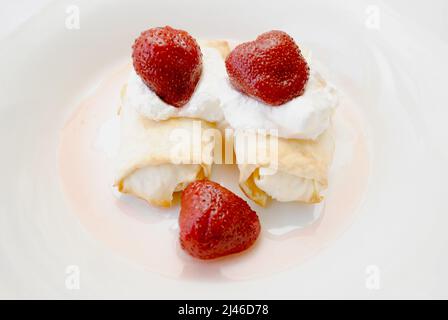 Käsecrepés serviert mit Schlagsahne und Erdbeeren Stockfoto
