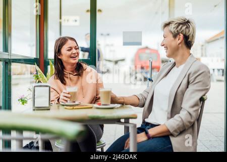 Zwei Freundinnen trinken Kaffee und genießen Zeit im Café am Bahnhof Stockfoto