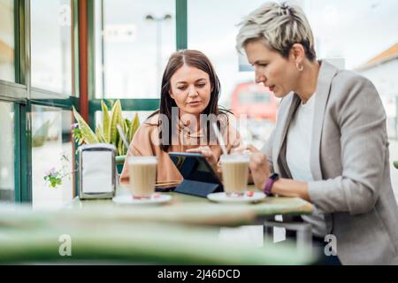 Zwei Freundinnen trinken Kaffee und genießen Zeit im Café am Bahnhof Stockfoto