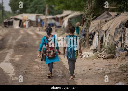 Neu-Delhi, Indien. 12. April 2022. Mädchen gehen zu einer provisorischen Schule unter einer U-Bahn-Brücke in Neu-Delhi, Indien, 12. April 2022. Die kostenlose Schule unter der U-Bahn-Brücke wird von einer Gruppe von Studenten für Kinder aus den Slums neben dem Fluss Yamuna betrieben. Quelle: Javed Dar/Xinhua/Alamy Live News Stockfoto