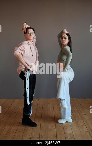 Zwei Jugendliche Vogue-Tänzer im aktiven Ohr halten ihre Beine im Knie gebeugt, während sie während des Trainings im Studio über neue Bewegungen arbeiten Stockfoto