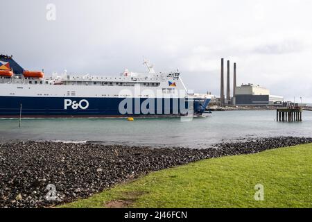 P&O Ferry European Highlander bei Ankunft im Hafen Larne in Co. Antrim. Schornsteine des Kraftwerks Ballylumford auf Islandmagee im Hintergrund sichtbar. Stockfoto