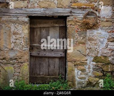 Eine alte Holztür in einem verrottten Haus in Poffabro, einem historischen mittelalterlichen Dorf im Val Colvera Tal in der Provinz Pordenone, Friaul-Julisch Giuli Stockfoto