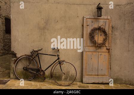 Eine alte Holztür und Fahrrad in Poffabro, einem historischen mittelalterlichen Dorf im Val Colvera Tal in der Provinz Pordenone, Friaul-Julisch Venetien, Nordöa Stockfoto