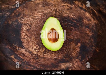 Avocado, der Liebling der Produce-Sektion. Hochwinkelige Aufnahme einer halbierten Avocado auf einem Holztisch. Stockfoto