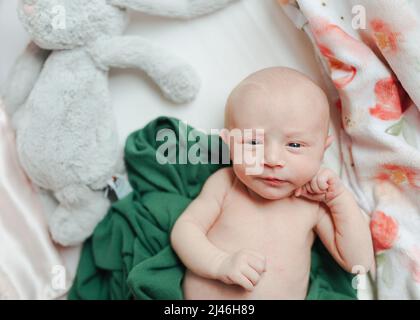 Neugeborenes Baby, das mit einem gefüllten Hasen auf Decken liegt Stockfoto