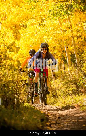 Ein Paar genießt eine Mountainbike-Fahrt im Herbst mit ihrem Hund Stockfoto