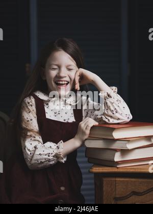 Porträt eines glücklichen Mädchens am Tisch mit Büchern. Stockfoto