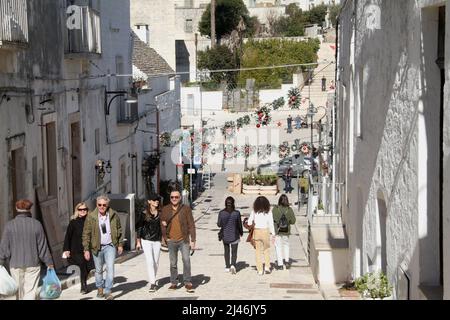 Besucher entlang der Straßen der malerischen Stadt Alberobello, Italien Stockfoto