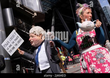 Eine Parodie von Boris Johnson wird mit einem anderen Klimaproter von Extinction Rebellion gesehen, der am 12.. April 202 in London, England, den Handel am Versicherungszentrum Lloyds of London, einem Versicherer fossiler Energieunternehmen, in der City of London, dem Finanzdistrikt der Hauptstadt, schließen konnte. Stockfoto