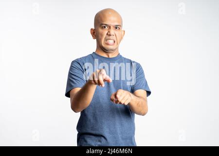 Wütender asiatischer Glatze zeigt im Stehen nach vorne Stockfoto