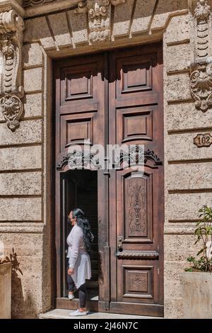 Vordere hohe Holztür im Kolonialgebäude des alten Havanna, mit schönen Zierschnitzereien. Stockfoto