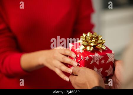 Vielen Dank für das Geschenk von Ihnen. Aufnahme eines nicht erkennbaren Geschäftsmanns und einer Geschäftsfrau, die in einem modernen Büro Weihnachtsgeschenke austauschten. Stockfoto