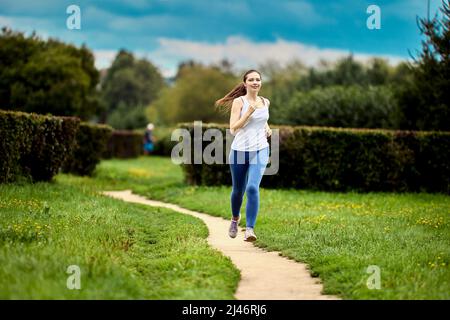 Im Stadtpark von einer jungen Frau am Sommermorgen laufen. Stockfoto