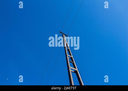 Alte rostige elektrische Stange vor blauem Himmel Hintergrund. Ansicht von unten. Stockfoto