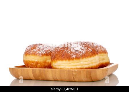 Drei süße Donuts gefüllt mit Marmelade auf einem Bambustablett, Nahaufnahme, isoliert auf weißem Hintergrund. Stockfoto
