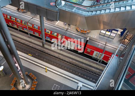 Blick auf den Hauptbahnhof von innen, wenn man auf die Bahngleise schaut. Ein roter Zug der Deutschen Bahn AG wartet auf Fahrgäste. Stockfoto