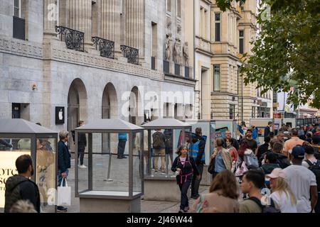 Eine Menge Leute warten vor dem Apple Store wegen einer neuen Version. Die Verbraucher sind begeistert und stehen in einer Schlange auf dem Bürgersteig. Stockfoto