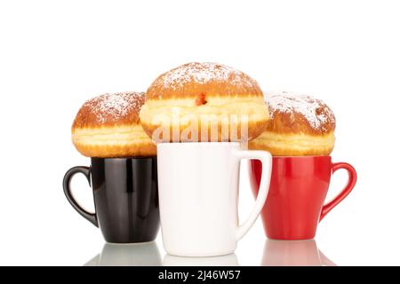 Drei süße Donuts gefüllt mit Marmelade mit drei Keramik-Tassen, Makro, isoliert auf einem weißen Hintergrund. Stockfoto