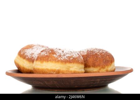 Drei süße Donuts gefüllt mit Marmelade auf einer Tonschale, Makro, isoliert auf einem weißen Hintergrund. Stockfoto