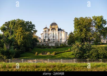 Große Villa direkt an der Elbe. Altes Luxusgebäude mit einem wunderschönen Garten und grünen Bäumen. Sonnenuntergang Sonnenlicht scheint auf das Haus. Stockfoto