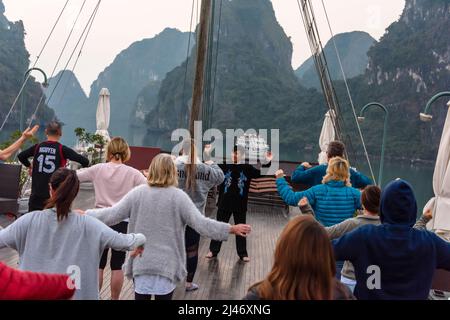 Halong Bay, Vietnam. 9.. Februar 2018. Touristen auf einem Schiff besuchen eine Tai-Chi-Sitzung bei Sonnenaufgang auf dem Deck. Stockfoto