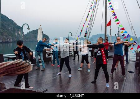 Halong Bay, Vietnam. 9.. Februar 2018. Touristen auf einem Schiff besuchen eine Tai-Chi-Sitzung bei Sonnenaufgang auf dem Deck. Stockfoto