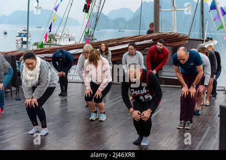 Halong Bay, Vietnam. 9.. Februar 2018. Touristen auf einem Schiff besuchen eine Tai-Chi-Sitzung bei Sonnenaufgang auf dem Deck. Stockfoto